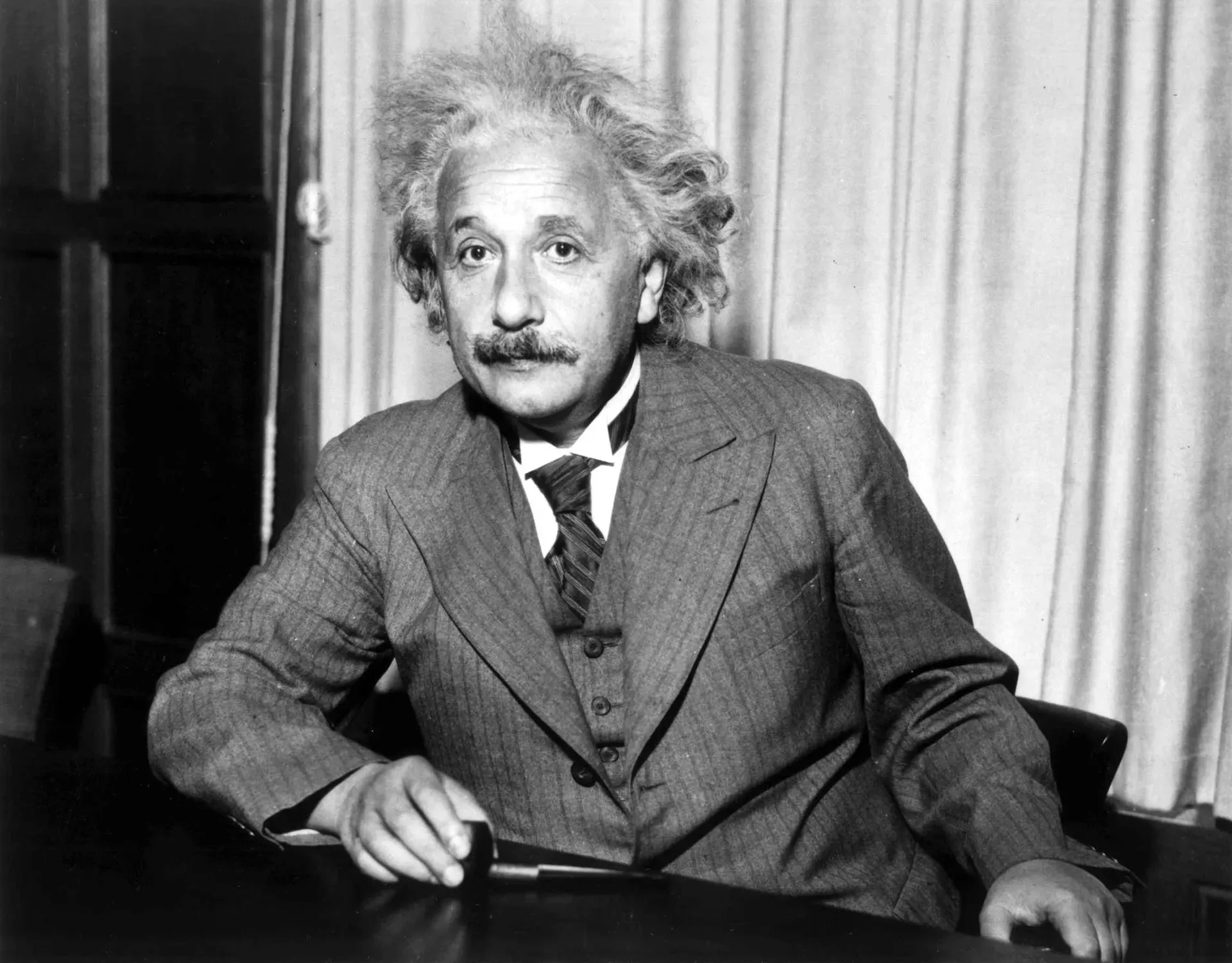 Albert Einstein in later life, seated, wearing a jacket and looking toward the camera.